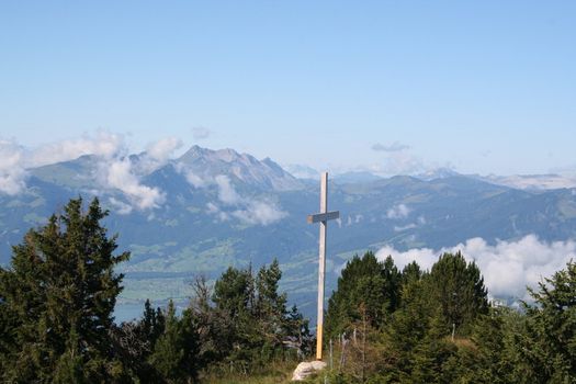 Cross in swiss alps with snow-capped mountain peaks in background