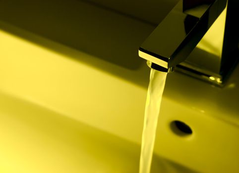 Closeup of modern bathroom tap in yellow