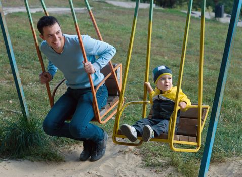 Happy father and cute son on a old swing 