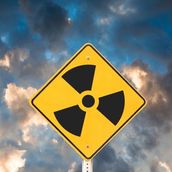 Road sign with radioactivity warning symbol on it with dramatic sky background.