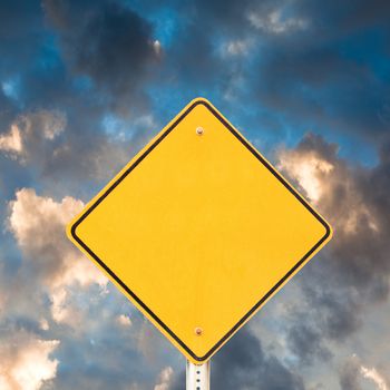 Blank yellow warning road sign with dramatic sky background ready to carry your message.