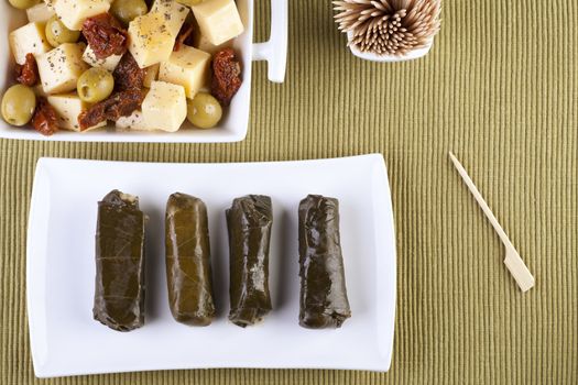 Tray of dolmas with cheese appetizer to the side, shot from directly above.