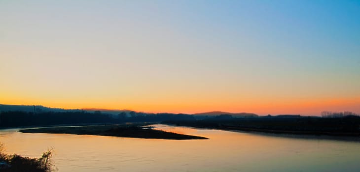 Beautiful sunset over the river, with silhouette of the coast