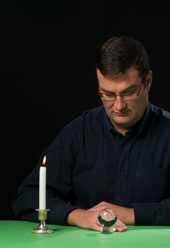 Man looking at his crystal ball meditating at candlelight