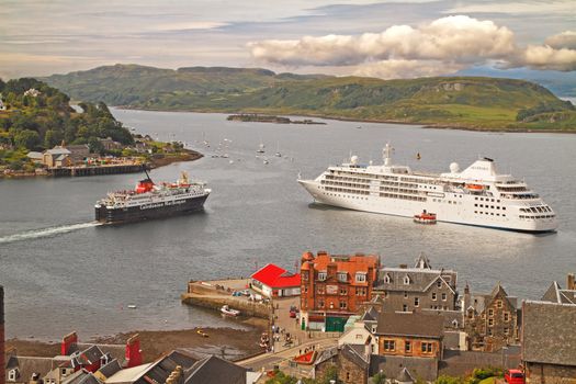 As the ferry leaves for the Western Isles, a cruise ship drops ancher at Oban on the Scottish west coast.