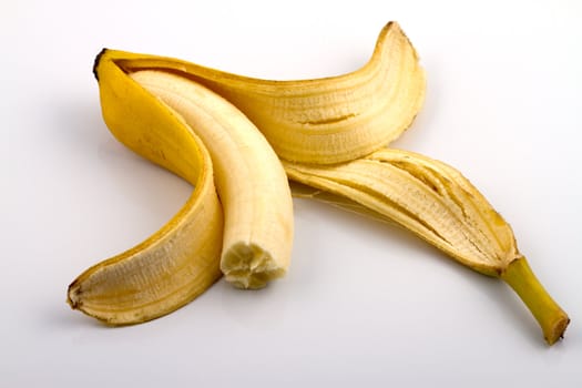 A peeled banana with bite marks on reflecting white background