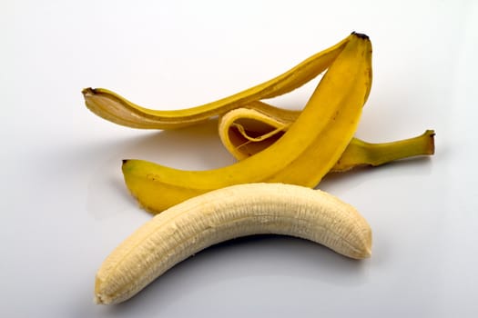 A hole peeled banana lying next to its peel