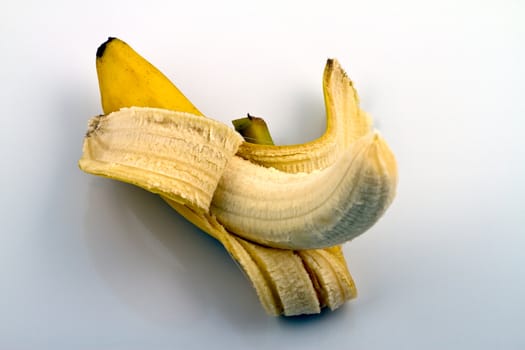 Peeled banana on reflecting white background