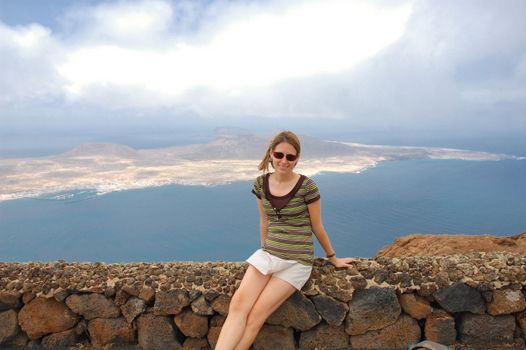 Young woman in Lanzarote with the small island of La graciosa in the background