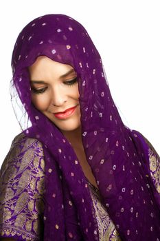 A beautiful young Indian or asian woman wearing a head scarf looking down smiling. Isolated over white