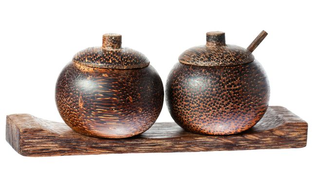 A pair of wooden old fasioned asian style salt and pepper bowls with lids and spoon. Isolated over white with clipping path.