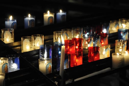 Close-up on lot of religious candles on a black support in a church