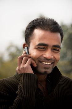 Portrait of a happy Indian businessman talking at cell phone