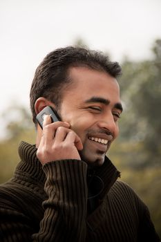 Portrait of a happy Indian businessman talking at cell phone
