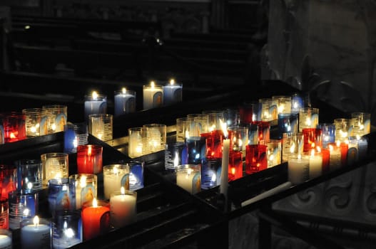 Lot of religious candles on a black support in a church