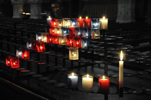 Many religious candles on a black support in a church