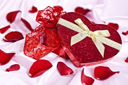 On a pink background gift box heart in the form of women's underwear, the background scattered rose petals.
