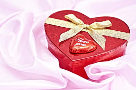 Pink bedding, gift box heart-shaped chocolate candy with the words I Love You. Surprise to the woman.
