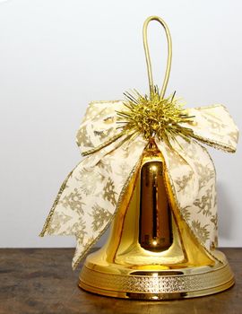 golden christmas bell with a decorative ribbon and gold tinsel