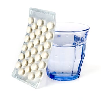 a blue glass and a blister with pills on a white background
