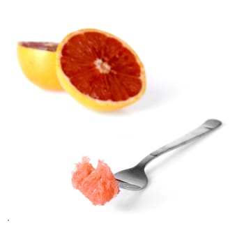 a fork with a piece of grapefruit on a white background