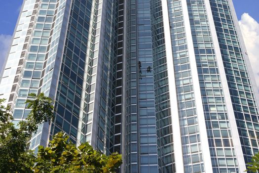 Two men working at heights cleaning window-abstract for risky job.