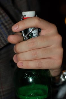 Man holding the neck of a bottle of beer