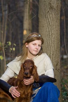 Portrait of the girl and irish setter in autumn forest.
