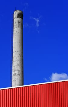 Red factory with a chimney against a blue sky
