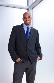 Good-looking smiling businessman standing near office window.