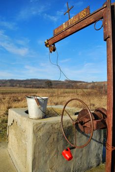 old draw-well in historical romanian village with bucket and red plastic cup