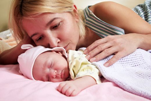 Mother with her sleeping newborn baby in home