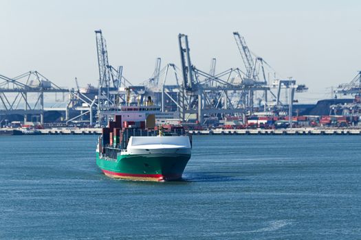 Containership on the river with industry and cranes in background