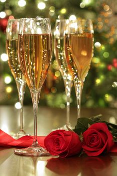 Glasses of champagne and red roses with festive background