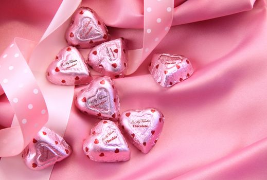 Valentine's chocolate hearts on pink satin with ribbon