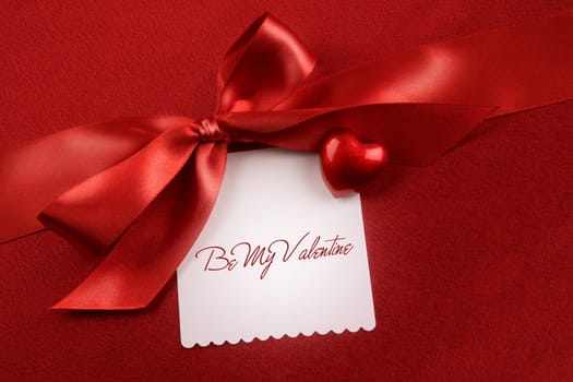 Satin bow and white card for gift on red background