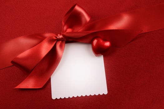 Satin bow and white card for gift on red background