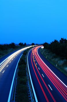 night traffic on busy highway with cars lights and blue sky