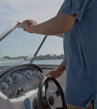 abstract concept portrait of man steering a speed boat in open waters with land in sight, copy space and crop margins