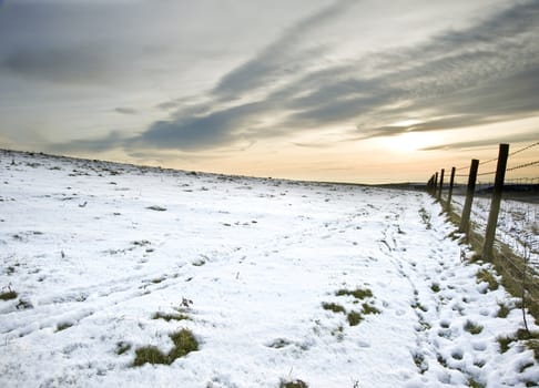 Winter snow landscape over fields with glowing sunset