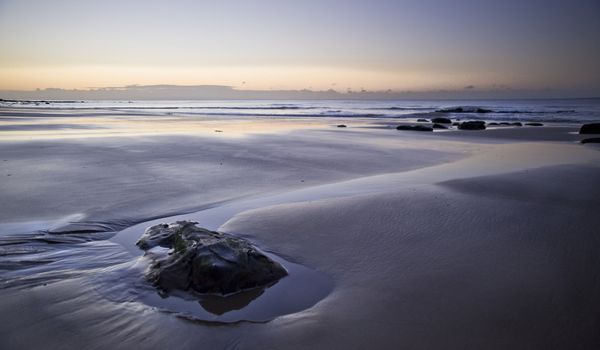 Beautiful view of beach at sunrise with rock details