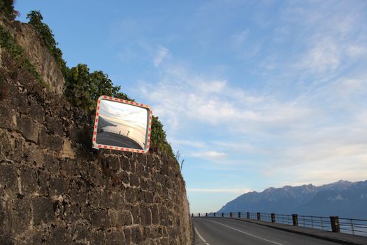 Side of a road with a little rock cliff and a mirror on it, in Lavaux countryside, Switzerland