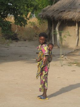 young girl carrying a baby in a traditional way