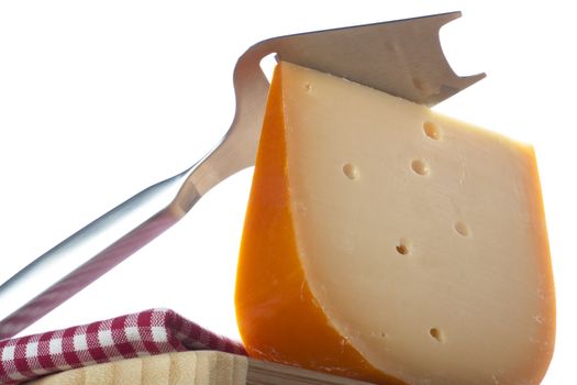 Wedge of cheese with slicer on white background.