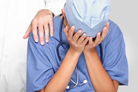 Crying upset nurse / doctor with problems having stress breakdown at work. Colleagues comforting her.