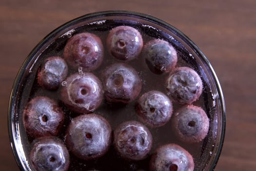 A shot of grape juice with grapes floating in it.
