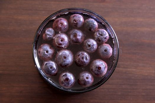 A shot of grape juice with grapes floating in it.
