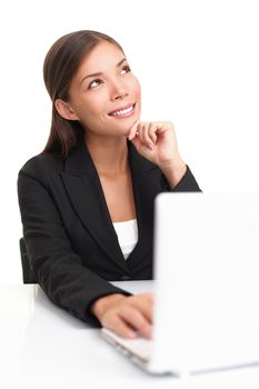 Businesswoman on laptop thinking looking up at copy space. Beautiful young business woman sitting by table isolated on white background.
