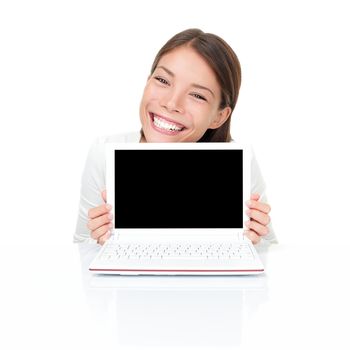 Woman showing netbook laptop screen copy space while sitting by white table. Asian Caucasian female model isolated on white background.