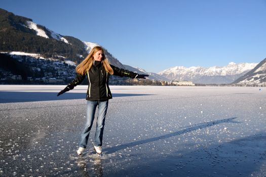 Young woman figure skating at frozen lake of zell am see in austria